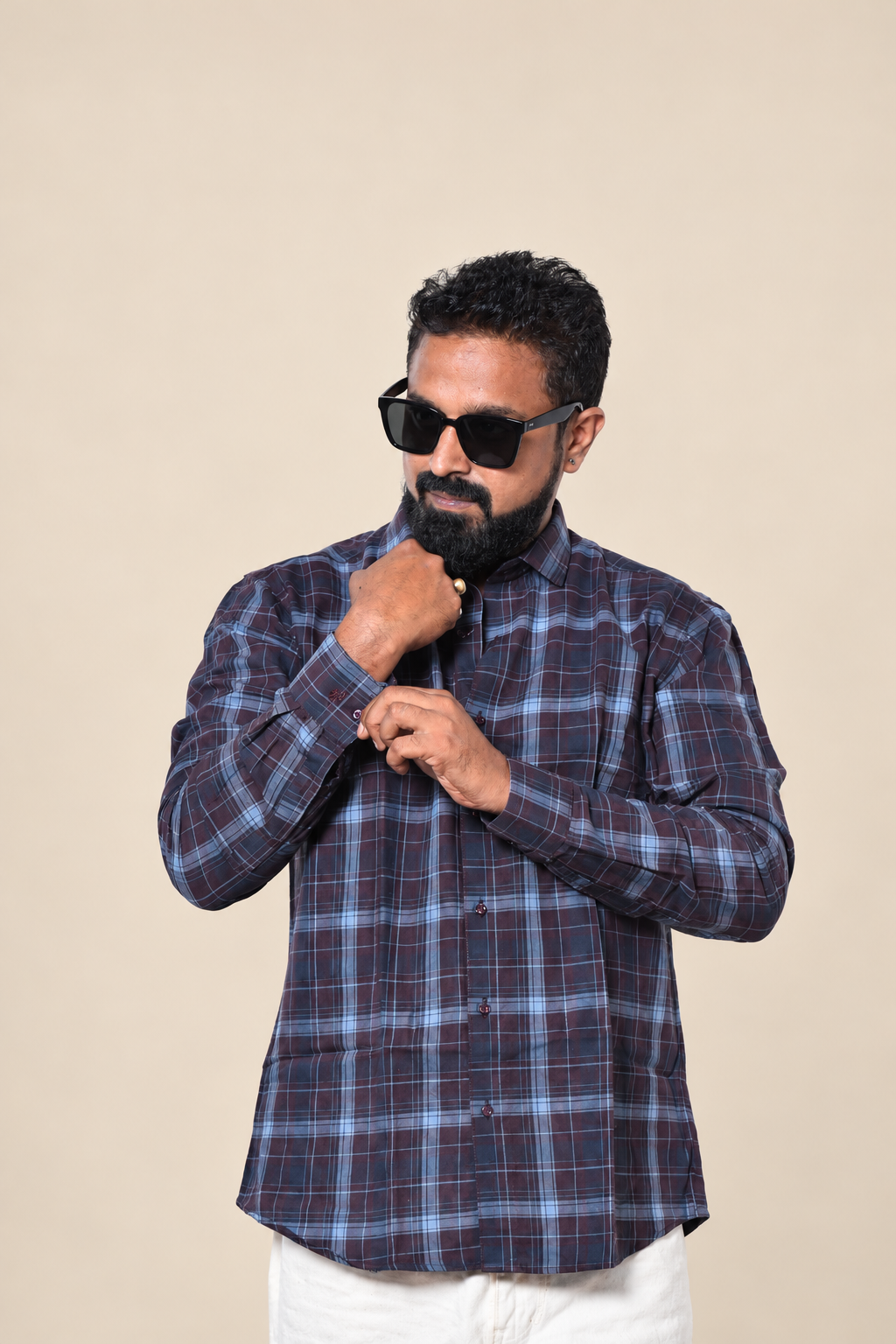 Man wearing a blue and burgundy checked shirt in a studio